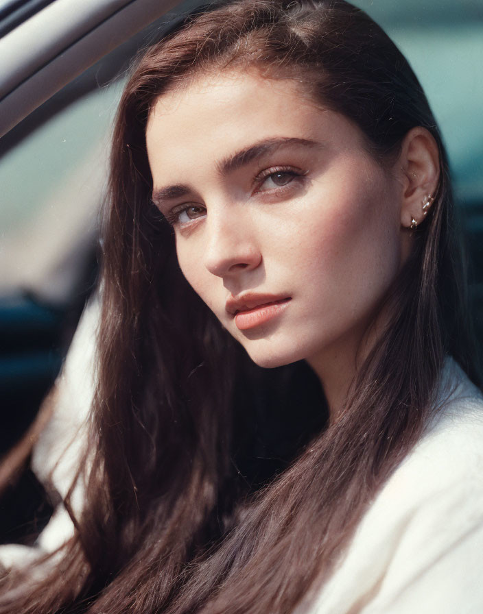 Woman with long hair in white top beside car portrait.