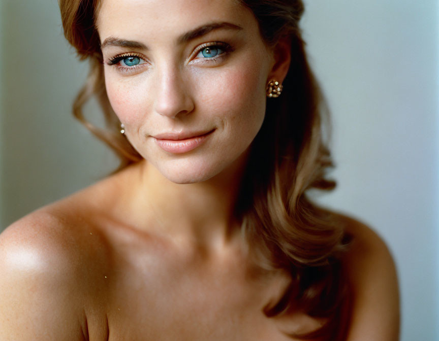 Portrait of woman with blue eyes, subtle makeup, diamond earrings, and cascading hair.