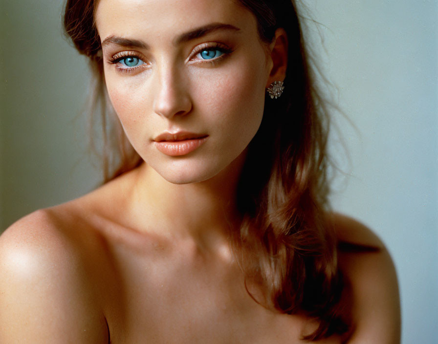 Portrait of woman with striking blue eyes and small earring, hair swept to side