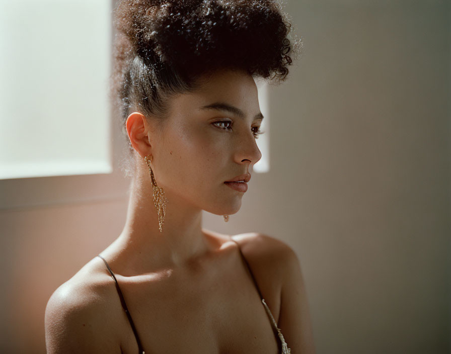 Elegant woman with updo and dangle earring in contemplation