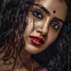 Woman Wearing Gold Jewelry and Bold Makeup on Dark Background