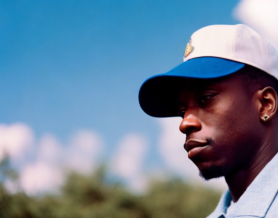 Pensive man in baseball cap against blue sky