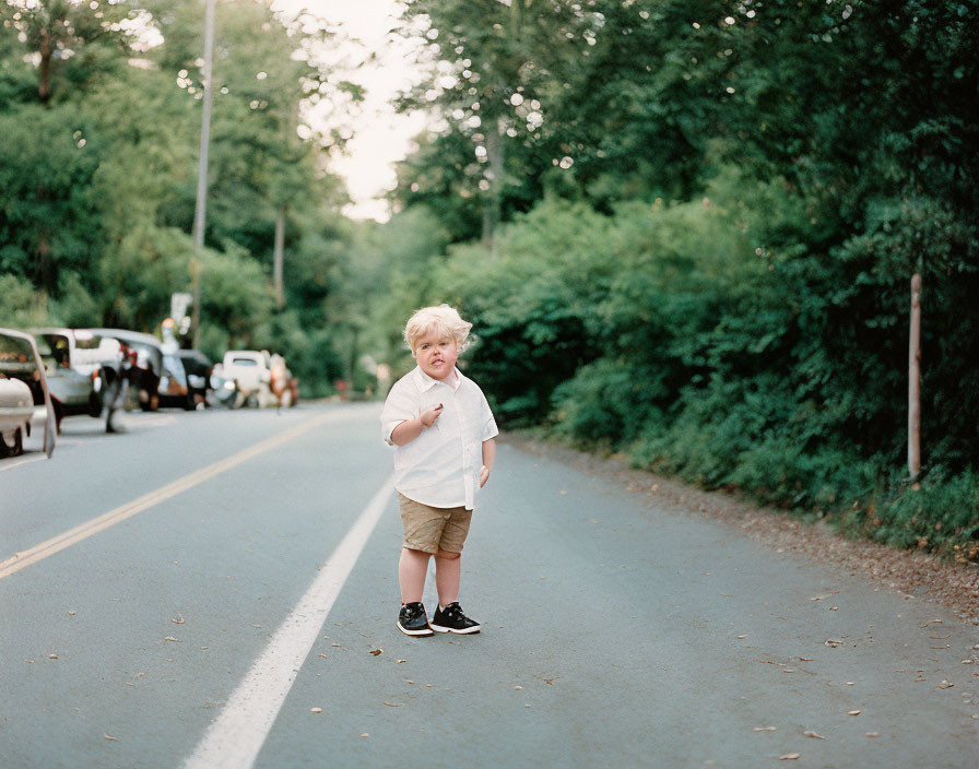 Blond-Haired Child in White Shirt on Road With Parked Cars