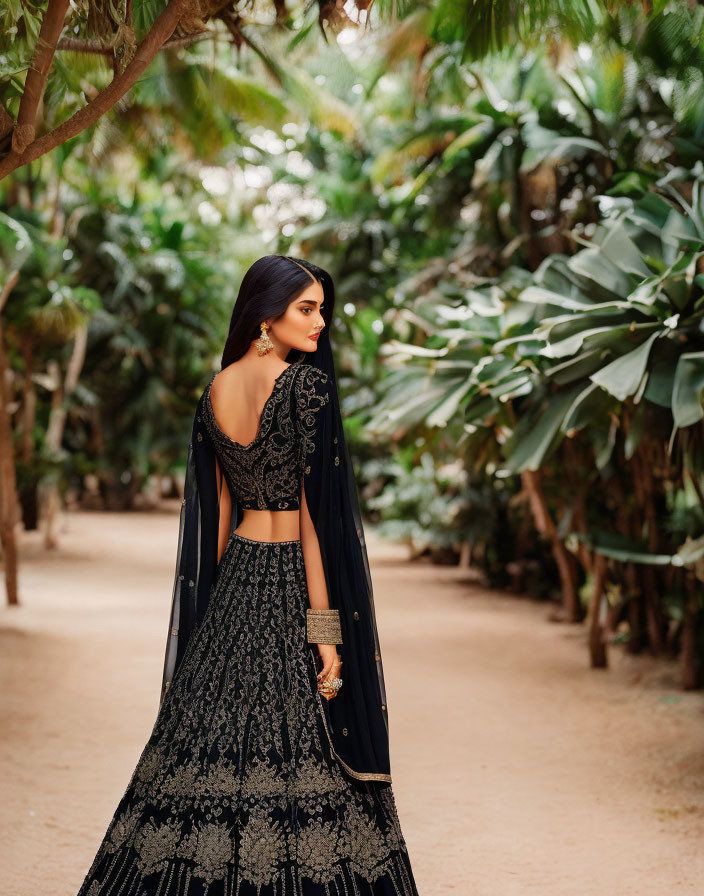 Elegant woman in black embroidered lehenga in lush garden setting