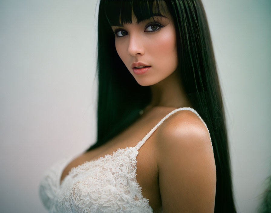 Long-haired woman in white lace garment, gazing at camera.