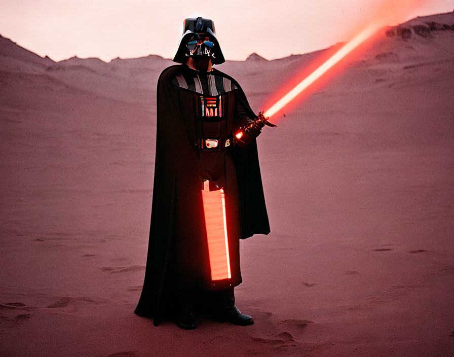 Cosplayer in Darth Vader outfit with red lightsaber in desert setting