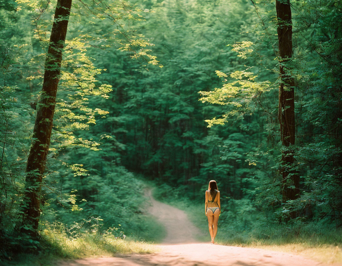 Woman in bikini strolling forest path with lush green trees