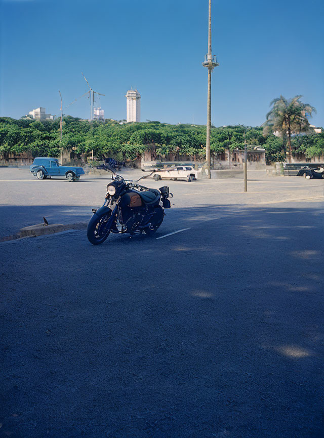 City street scene with parked motorcycle, cars, and high-rise buildings on sunny day