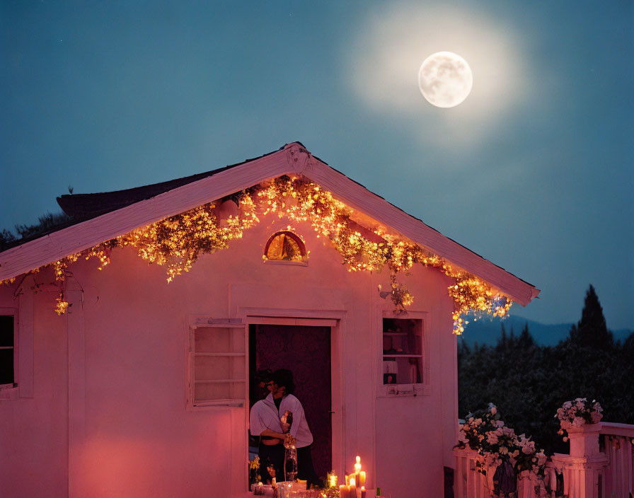 Couple embracing under twinkling lights with full moon in dusky sky