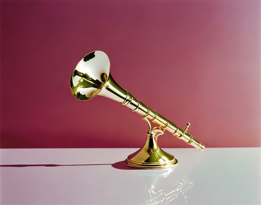 Shiny gold trumpet on pink background with reflective surface