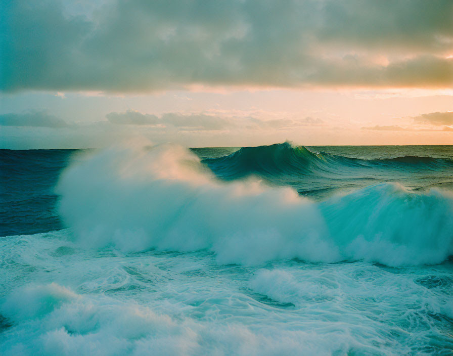 Energetic ocean waves under serene sunset sky