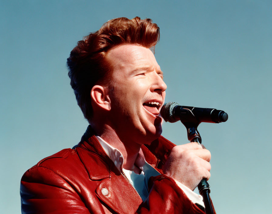 Passionate man in red jacket singing under clear blue sky