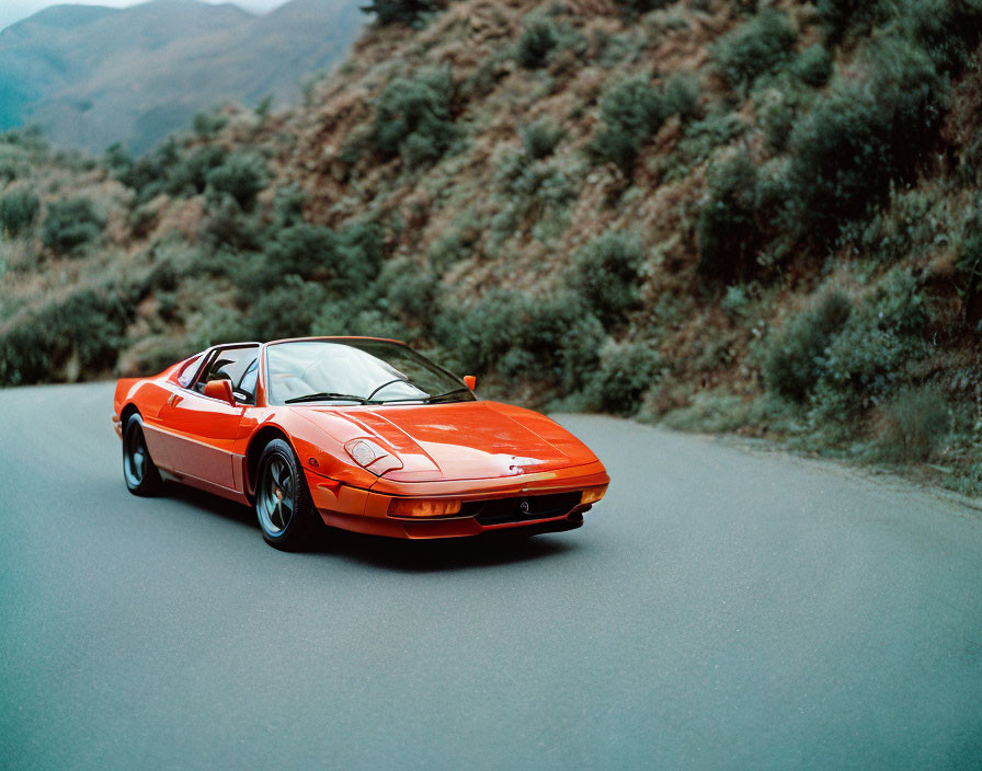 Red Sports Car on Mountain Road with Lush Greenery