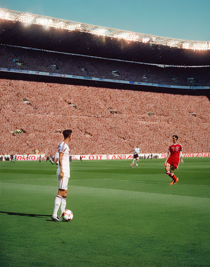 Soccer players in white and blue striped kit and red kit at packed stadium