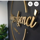 Stylish modern sign with gold 3D "Agency" lettering on textured black wall