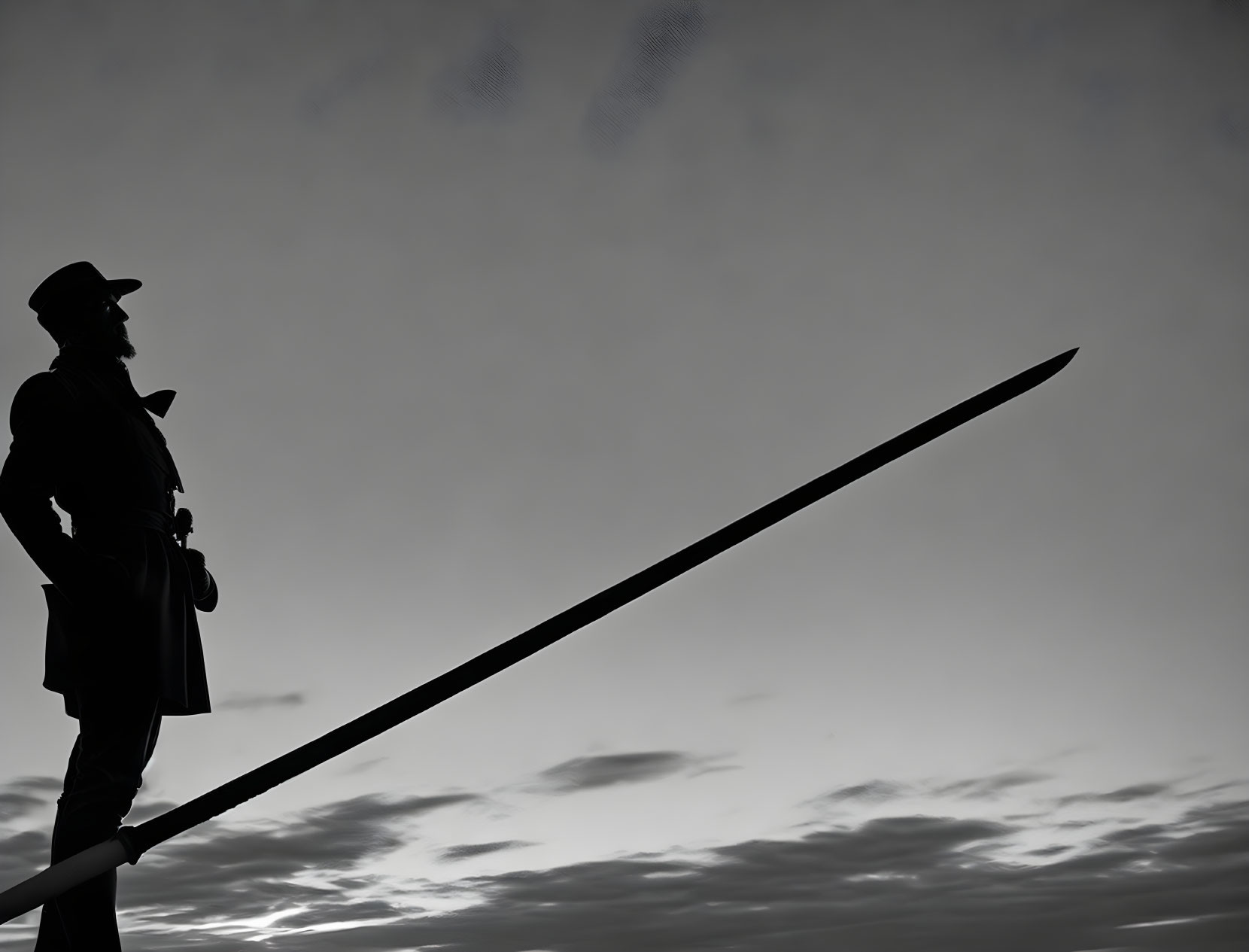 Confident person silhouette with hat and pole against cloudy sky