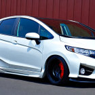 Sporty White Hatchback with Custom Black Rims Parked in Front of Red Structure