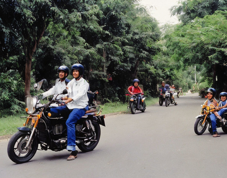 Motorcycle riders on tree-lined road.