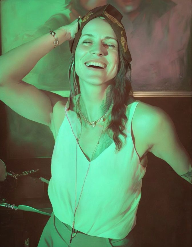 Joyful woman laughing under green light in sleeveless top.