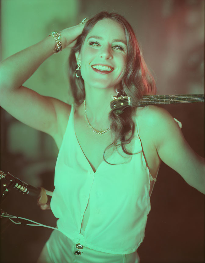 Smiling woman holding guitar in warmly lit room