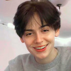 Smiling young man with dark wavy hair in light blue shirt