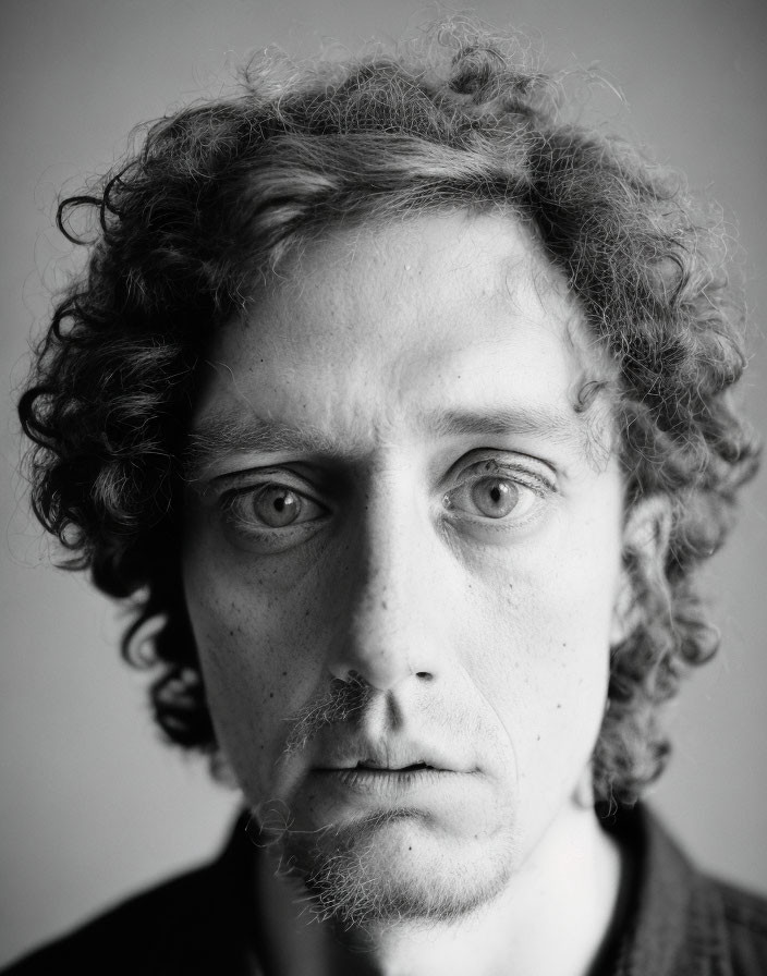 Monochrome portrait of a person with curly hair and intense gaze