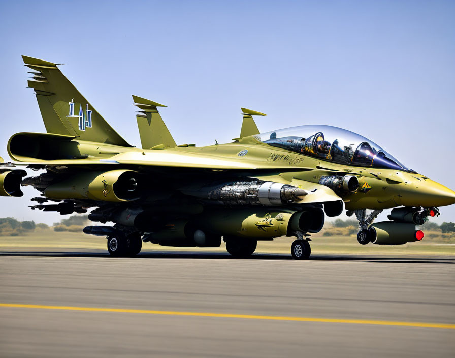 Yellow fighter jet with missile attachments on a runway under clear skies