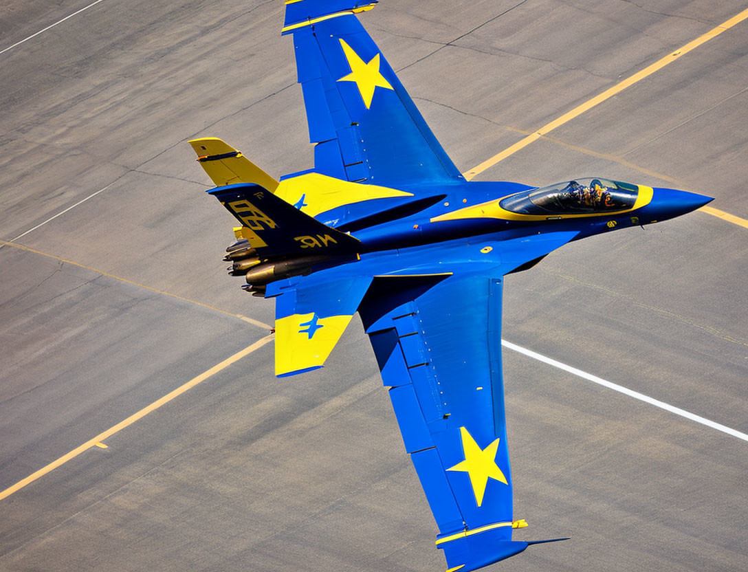 Blue and Yellow Fighter Jet with Star Emblems Flying Low Over Tarmac