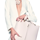 Stylish woman in white pantsuit with pink handbag and gold earrings