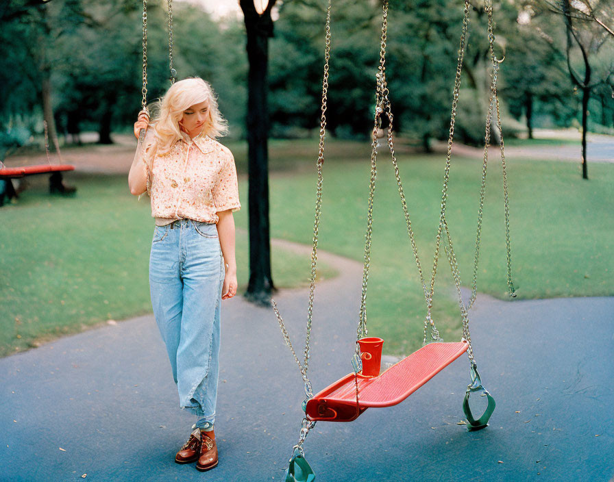 Vintage-clad woman by red swing in park with green trees