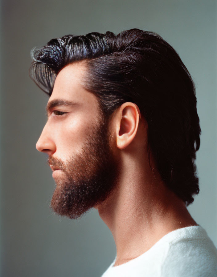 Man with Dark Hair and Full Beard in Profile Against White Shirt