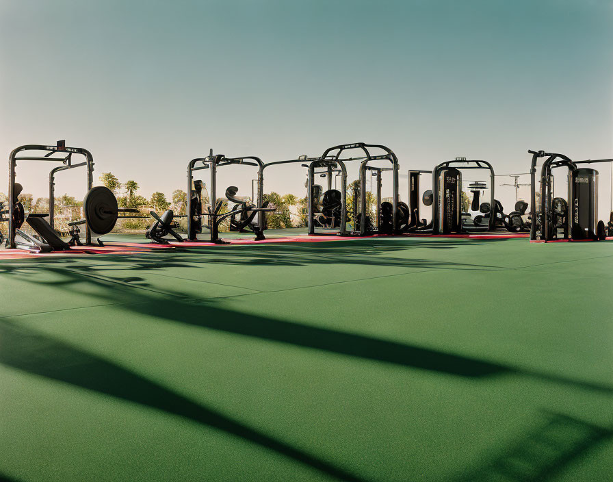 Outdoor Gym with Green Flooring and Weightlifting Machines Under Clear Skies