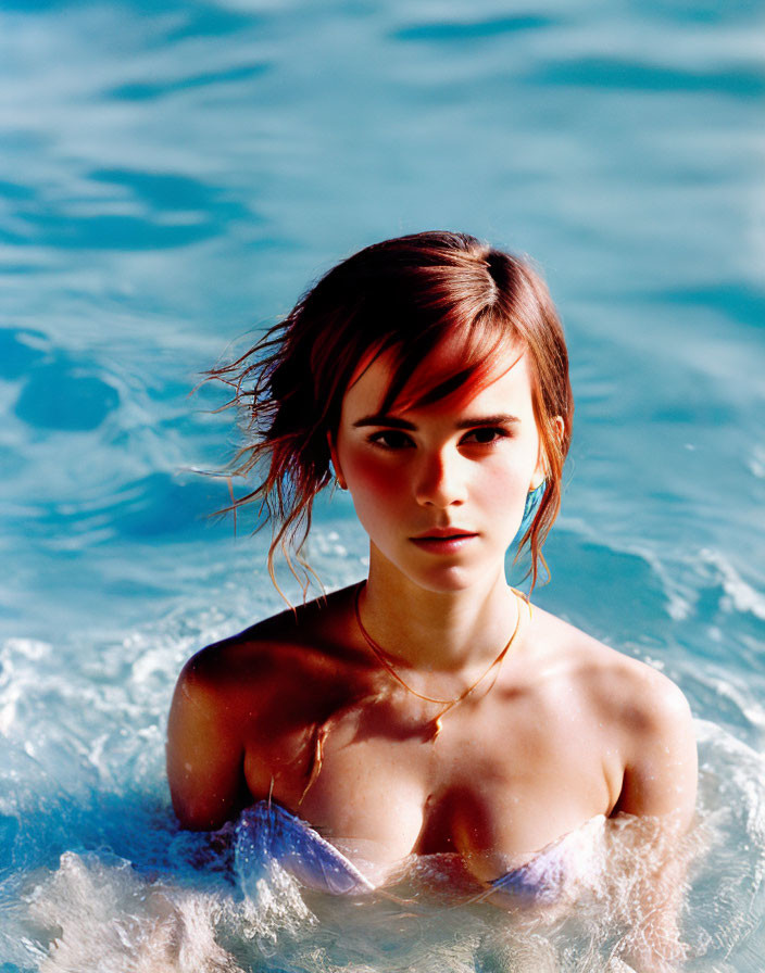 Portrait of young woman in pool with wet hair and blue top