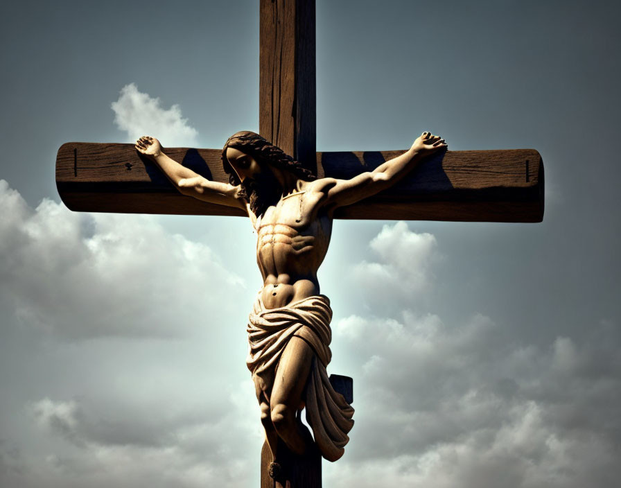 Christian crucifix statue against cloudy sky symbolizing crucifixion