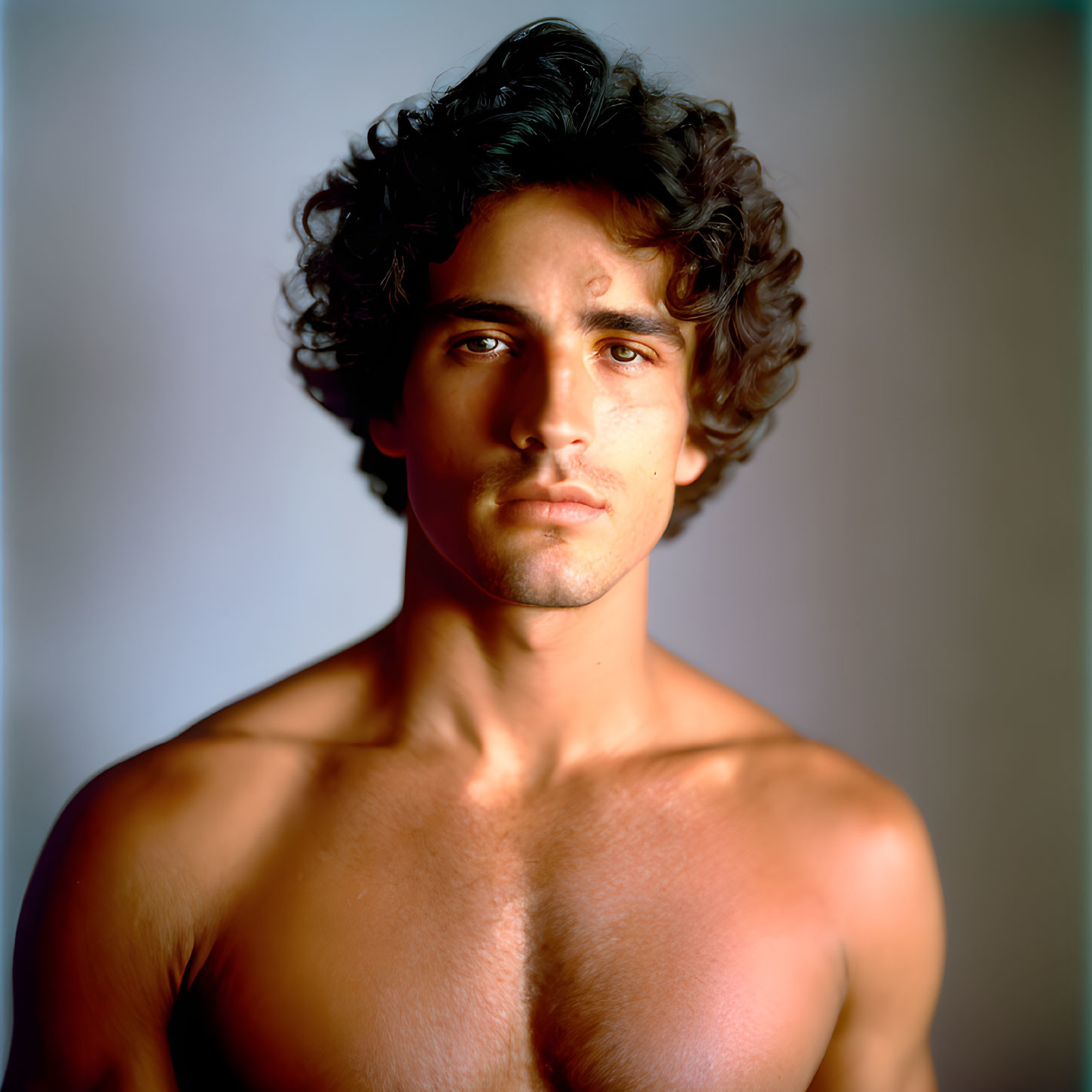 Intense shirtless man portrait with tousled hair and subtle shadow