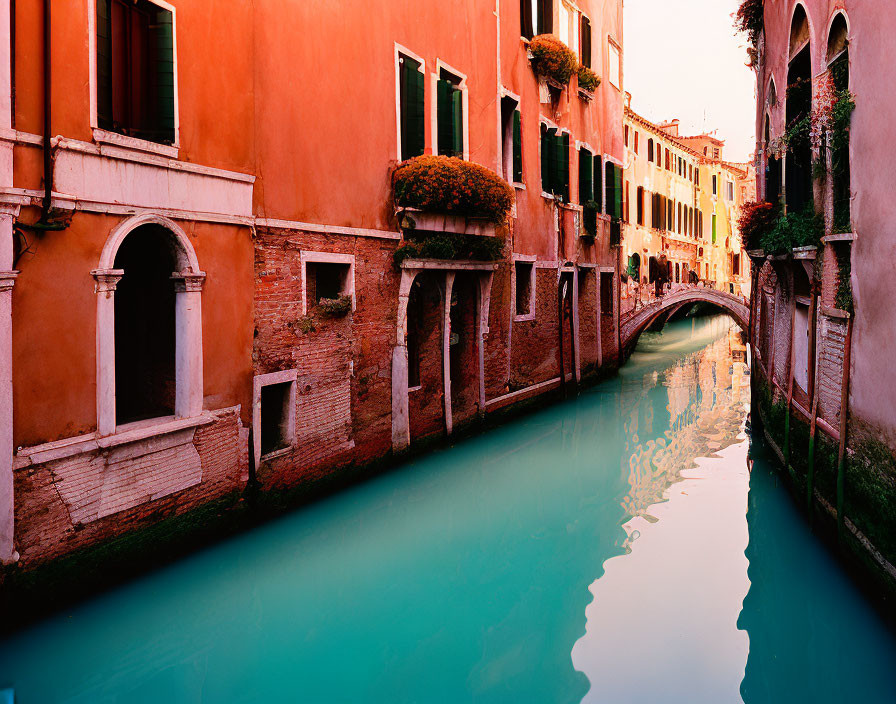 Tranquil canal with emerald waters and red buildings by a bridge