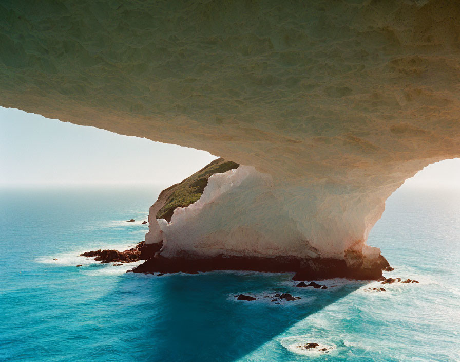 Scenic view of rugged coastline from cave with natural arch & cliffs