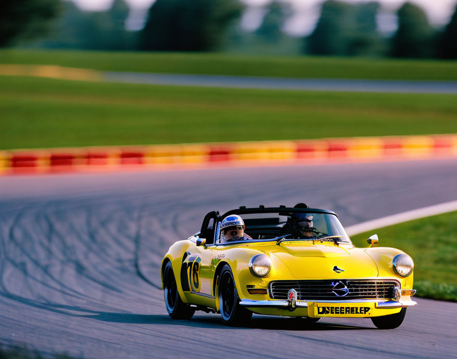 Vintage yellow sports car with number 18 racing on track with two people inside.