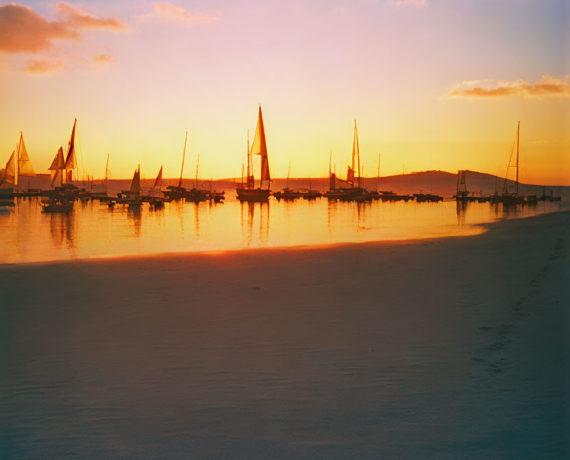 Tranquil beach sunset with sailboats in calm waters