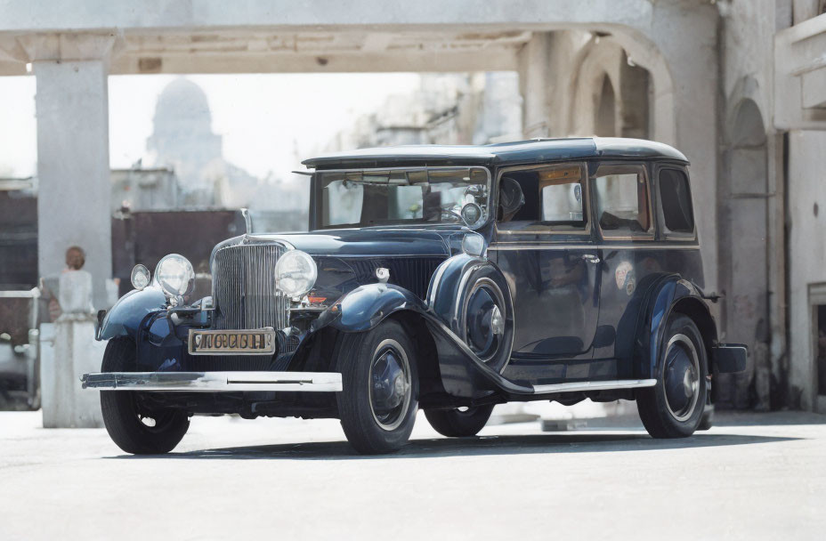 Vintage black car with chrome accents and spoked wheels parked near historical buildings.