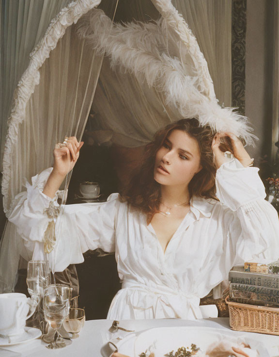 Person adjusting feathered headband at elegant vintage table under canopy