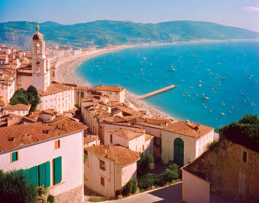 Scenic coastal town with terracotta roofs and boats on curved beach