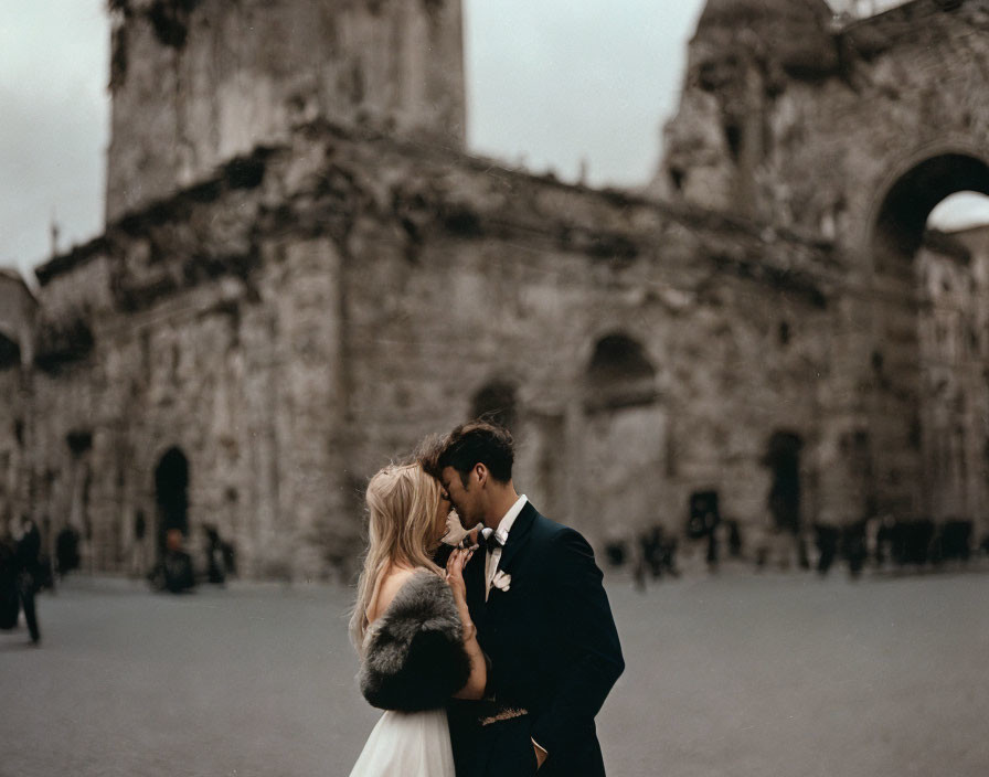 Wedding couple sharing intimate moment at historic stone archway