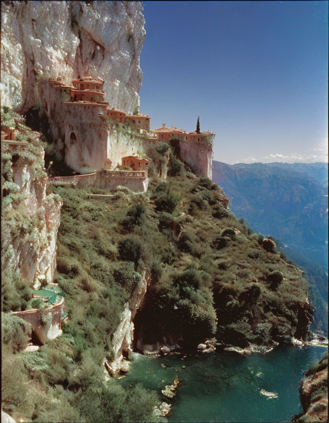 Monastery built into rugged cliff with valley backdrop