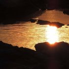 Scenic sunset over rocky shoreline with sun reflection and steam rising