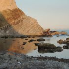 Scenic view of rugged cliffs, calm waters, and blooming bushes