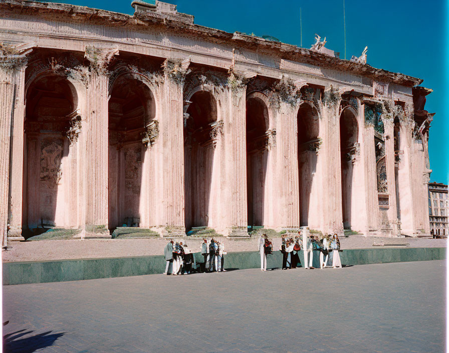 Group of people at ancient Roman building with tall Corinthian columns