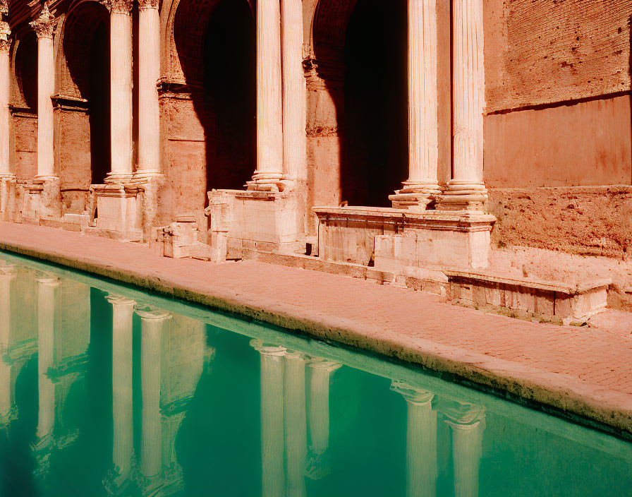 Ancient columns reflected in serene water pool under clear blue sky