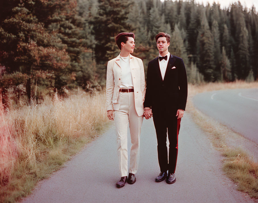 Couple in white suit and black tuxedo walking in forest setting