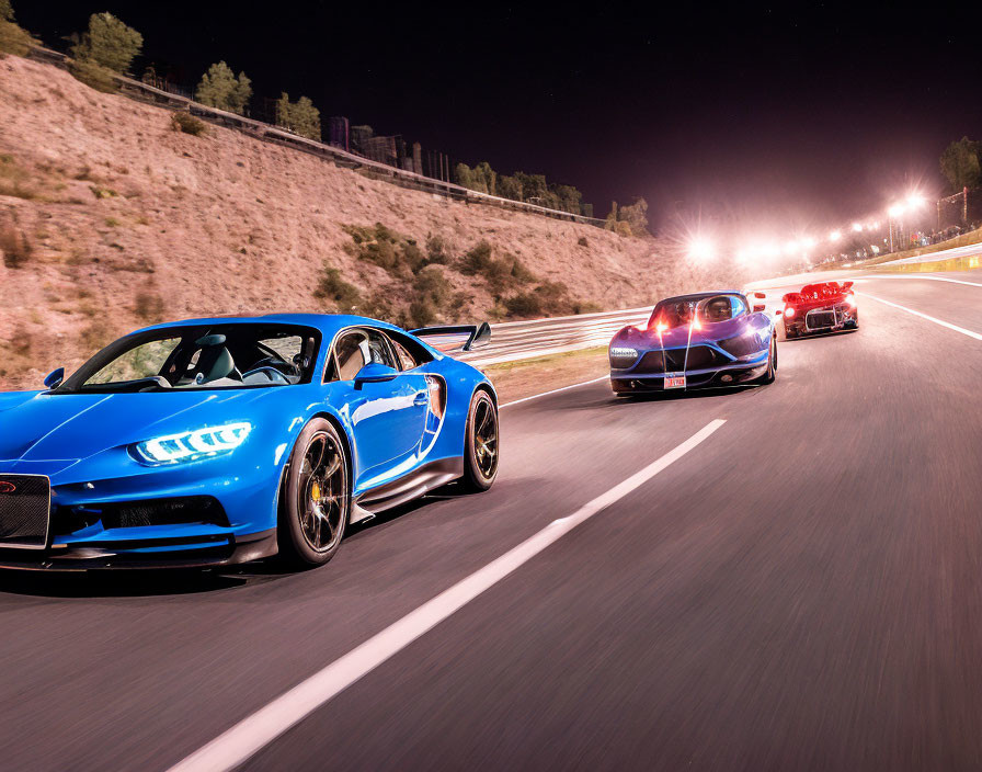 Speeding luxury sports cars on illuminated night racetrack